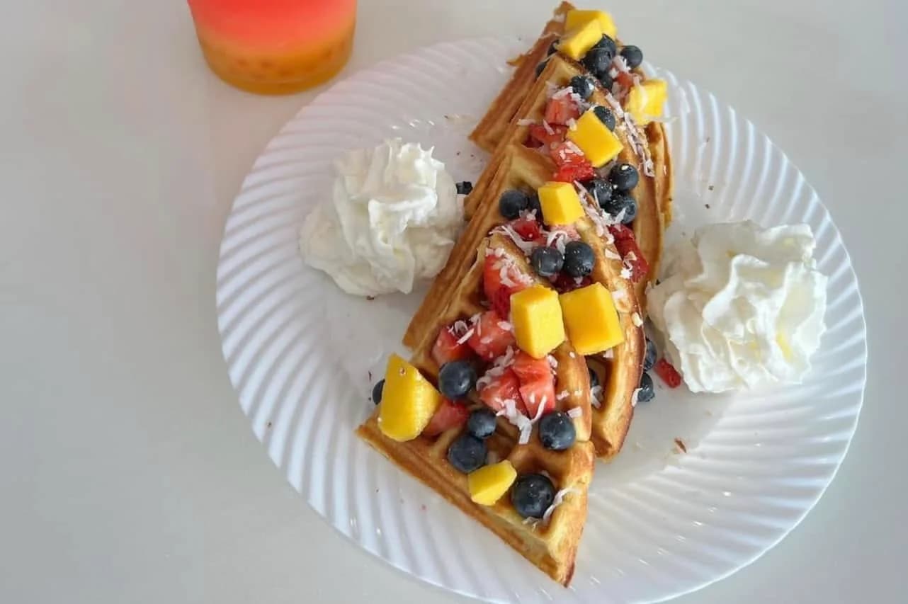 Protein waffles topped with mango, strawberries, blueberries, and coconut